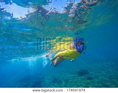 Woman in snorkeling mask underwater photo. Female snorkel above sea bottom and corals. Sportswoman in modern swimming gear. Sea exploring in mask with pipe. Young coral reef ecosystem in tropical sea.