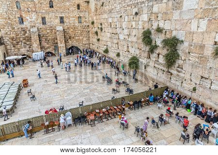 JERUSALEM, ISRAEL - MAY 23, 2016: Prayers making their wishes and prays at the Western Wall, Wailing Wall or Kotel witch is located in the Old City, view from the Mughrabi Bridge.