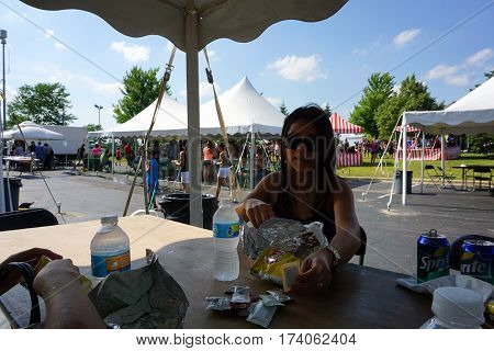 JOLIET, ILLINOIS / UNITED STATES - JUNE 25, 2016: A woman eats food at the Wesmere Country Club Subdivision's annual Wesmere Summerfest in Joliet.