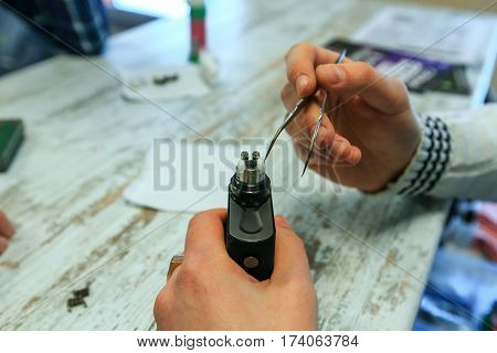 Male Hands Fill Cotton Wool For The E-cigarette. After-sales Service Of The Electronic Cigarette. En