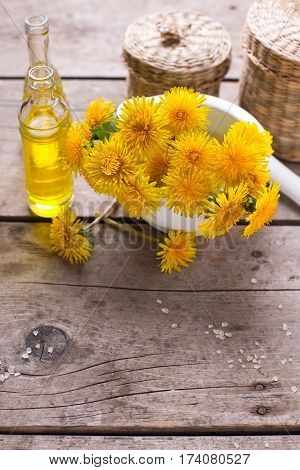 Yellow flowers tussilago in mortar on wooden background. Wellness setting. Selective focus. Vertical image.