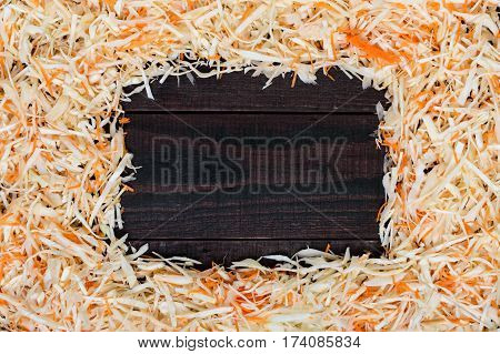Frame made of salad. Fresh chopped cabbage and carrots. In the middle of a dark wooden space for your notes. Healthy food concept. Lenten menu.