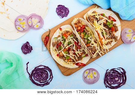 Spicy Mexican tacos with minced meat mashed beans vegetables grated cheese. The top view