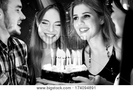 Black white pictures of happy friends birthday wear in hat party with candle celebration cakes. People looking at burning candles. Two women and man have fun.