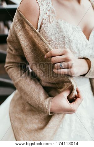Bride dress on sweater to get warm. Noface, close-up