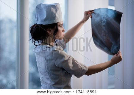Caucasian woman looking at x-ray picture of backbone