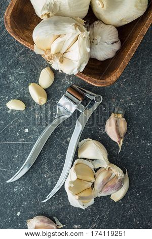 Garlic and garlic press on kitchen table. Top view.
