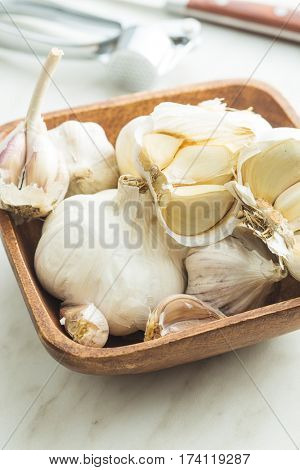 Fresh garlic in wooden bowl on kitchen table.