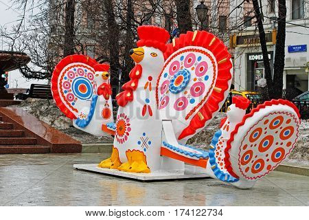Moscow Russia - February 21 2017: Traditional Dymkovo toy Cock as art object and swing at Russian national festival 