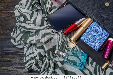 Women's clutch bag and accessories on a dark wooden background