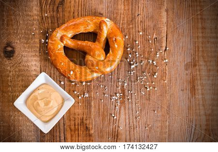 Bavarian pretzel with mustard on wooden table.