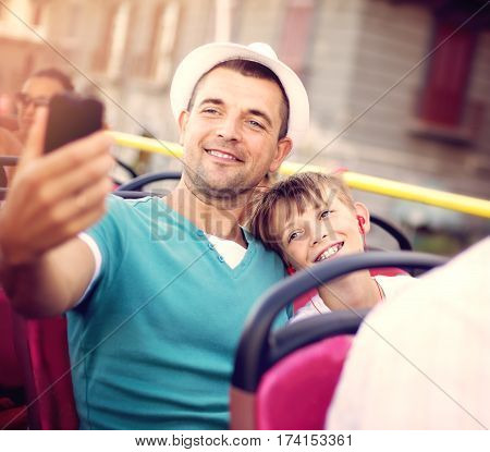 Father with his son traveling by tour bus and taking selfie