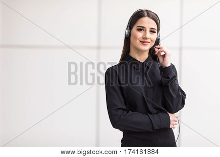 Portrait of smiling cheerful customer support phone operator in headset against office background