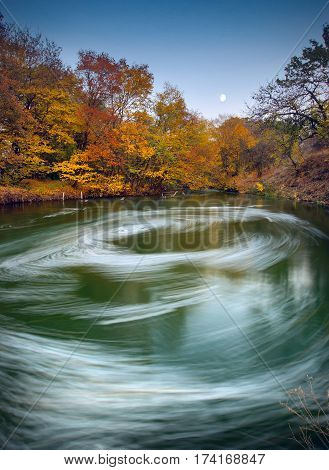 Moonrise over the Autumn river with whirlpool