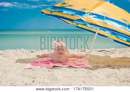 Cure baby laying on the sunbed under umbrella at the beach of Black sea