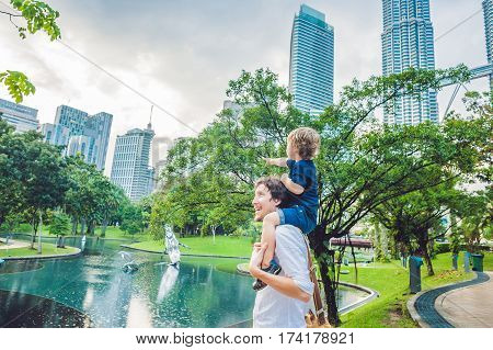 Father And Son Travelers In Malaysia Against A Background Towers Patronas Twins. Traveling With Chil