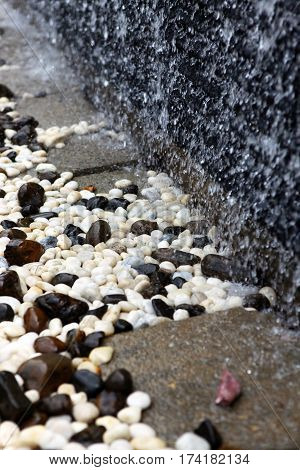 Colored pebbles at the bottom of the artificial waterfall in hotel's interior