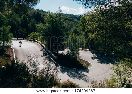 A silhouette of a cyclist descending a switchback curve in the dark forest
