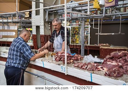KIEV UKRAINE - AUGUST 10 2015: Butchers playing chess next to the meat they are selling inside Besarabsky market one of the iconic markets of Kiev The Besarabsky Market also referred to as the Besarabka is an indoor market located in the center of Kiev