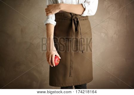 Woman wearing apron on color background