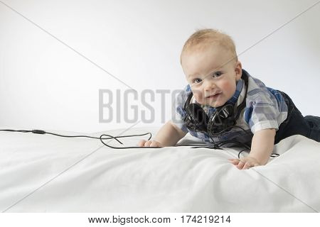 Cute baby boy with headphones on his head looling at camera and smiling