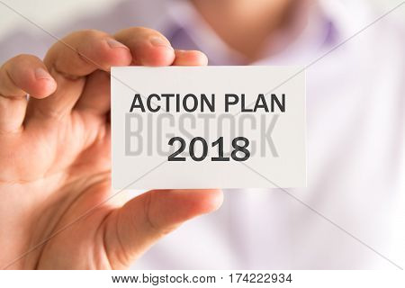 Businessman Holding A Card With Action Plan 2018 Message