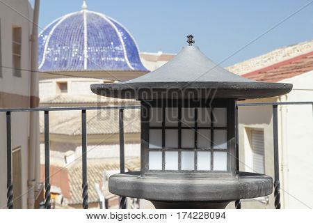 foreground of a decorative street lamp with the dome of San Bartolome church in the background taken on Petrer in the province of Alicante spain