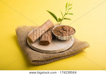 Ayurvedic Chandan powder or sandalwood paste in silver bowl with sticks and leaves placed over sahan or sahana or circular stone base for creating paste