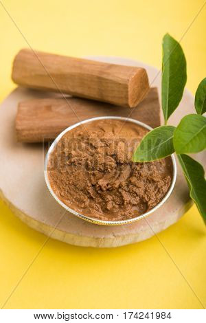 Ayurvedic Chandan powder or sandalwood paste in silver bowl with sticks and leaves placed over sahan or sahana or circular stone base for creating paste