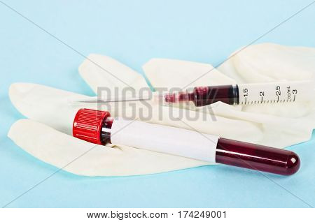 Blood sample in tube for testing with gloves and needle syringe.