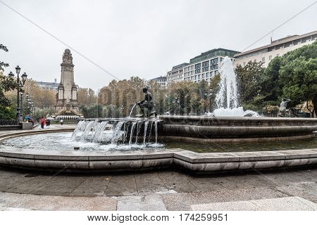 Madrid Spain - November 20 2016: Rainy day in Spain Square of Madrid. Fountain and Cervantes monument on background