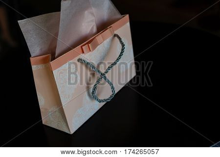 set of scarlet bordo pink coral and purple lipsticks with present bag on black fur background side view Pink gift bag black background