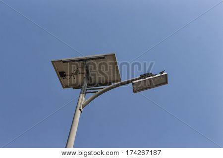solar pannel and LED street lamp pole on blue sky and a bird