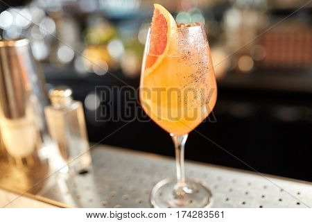 alcohol drinks and luxury concept - glass of grapefruit cocktail at bar