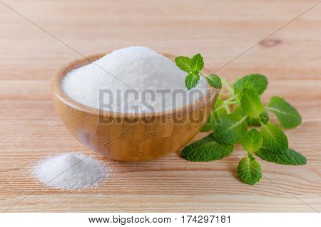 birch sugar xylitol in a wood bowl with mint on wooden background