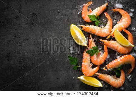 Prawns Shrimps with lemon in ice on slate background. Top view copy space. Food background.
