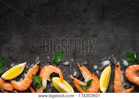 Prawns Shrimps with lemon in ice on slate background. Top view copy space. Food background.