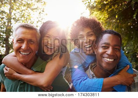 Mature Friends Giving Piggybacks In Backyard Together