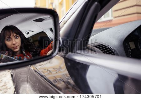 Reflection of young woman driver in car miror