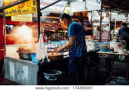 CHIANG MAI THAILAND - AUGUST 27: Man cooks food at the Saturday Night Market on August 27 2016 in Chiang Mai Thailand.