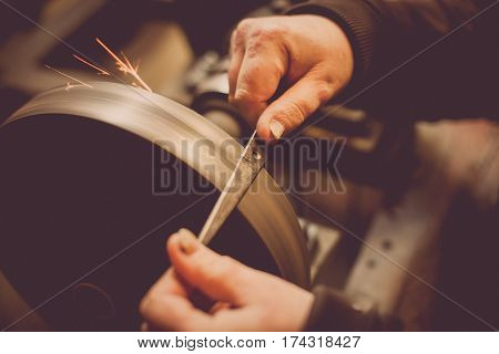 Close up shot of a man's hands sharpening a scissors.