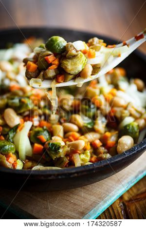 Brussels sprouts roasted with vegetables and beans in a frying pan