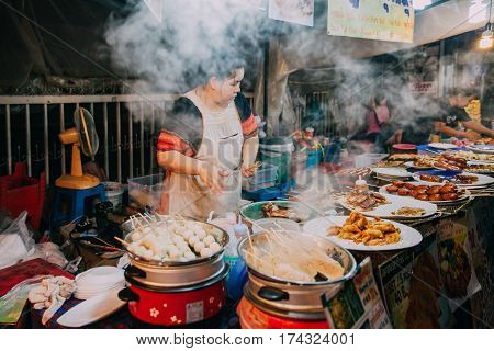 CHIANG MAI THAILAND - AUGUST 27 Thai woman cooks food for sale at the Saturday Night Market on August 27 2016 in Chiang Mai Thailand.