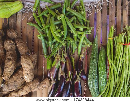 Sweet potato and eggplant with other vegetables on wood table. Farm market in tropical country. Exotic vegetables on table for sell. Fresh ripe vegetables of Philippines. Natural still life flat photo