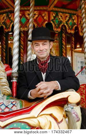 IRONBRIDGE UK - CIRCA 2013: Attendant in costume riding a carousel at the fairground in Blists Hill Victorian Museum Ironbridge UK