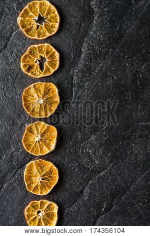Dry Slices Of Citrus Fruits On A Black Slate Background.