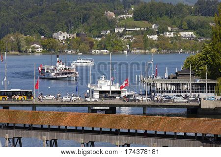 LUCERNE SWITZERLAND - MAY 06 2016: Roofed Chapel Bridge traffic jam on the Seebruecke and many boats on Lake Lucerne together with many houses among trees it shows the tourist nature of the town