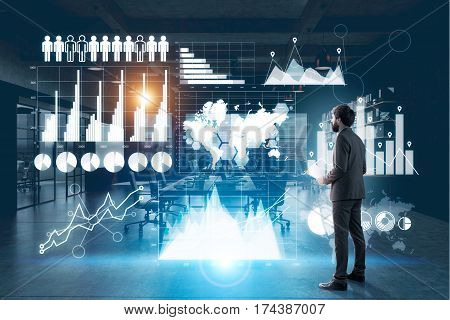 Side view of a businessman with a paper cup of coffee standing near a glassboard with multiple graphs drawn on it. Toned image.