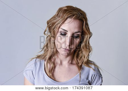 blond attractive woman on her thirties sad and depressed looking desperate in sorrow and grief facial expression in female depression emotion concept isolated on grey background