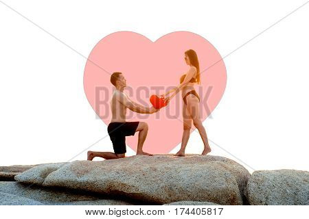 Lovely young adult couple standing on the rocks above tropical sea in isolated.
